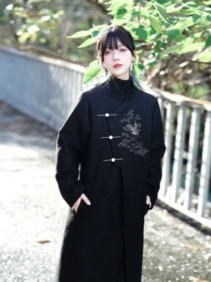 Three-quarter view of a black Chinese style embroidered Hanfu coat with asymmetrical placket, thick tweed fabric, and practical side pockets