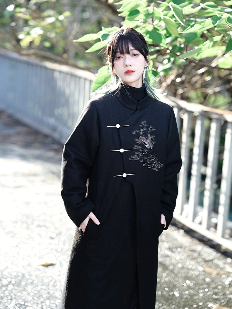 Three-quarter view of a black Chinese style embroidered Hanfu coat with asymmetrical placket, thick tweed fabric, and practical side pockets
