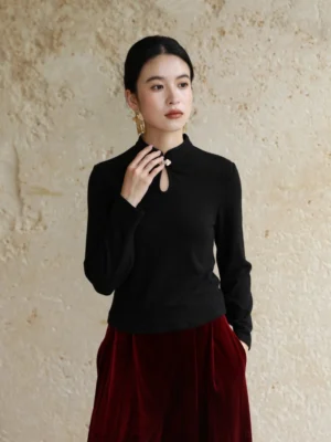 Black Chinese-style long sleeve ribbed knit top with metal frog clasp and elegant stand collar shown from the front three-quarter view