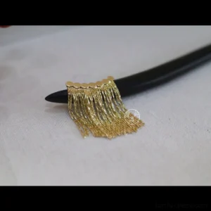 Close-up flat lay of black curved wooden Chinese hairpin with scalloped gold-tone chain tassel on linen fabric
