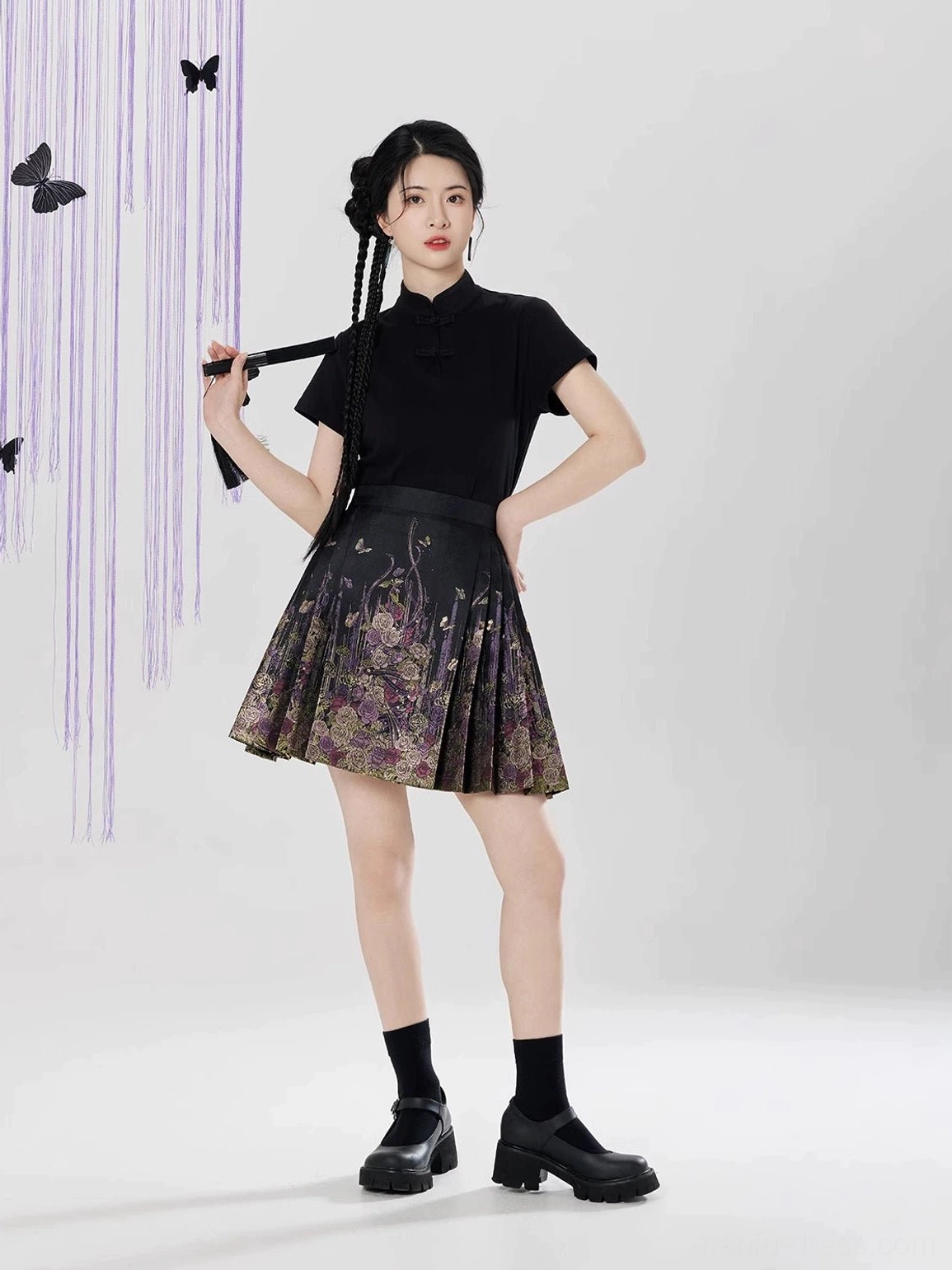 Side front view showing the pleated A-line silhouette of the black floral brocade mini mamian skirt