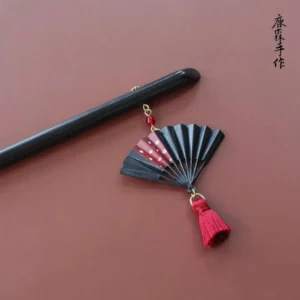 Black folding fan red tassel Chinese hair stick with polished dark wooden pin shown in flat lay detail view