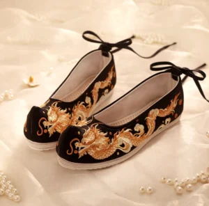 Black and gold dragon embroidered Hanfu shoes with upturned toes, black ankle ties and white rubber soles shown as a pair
