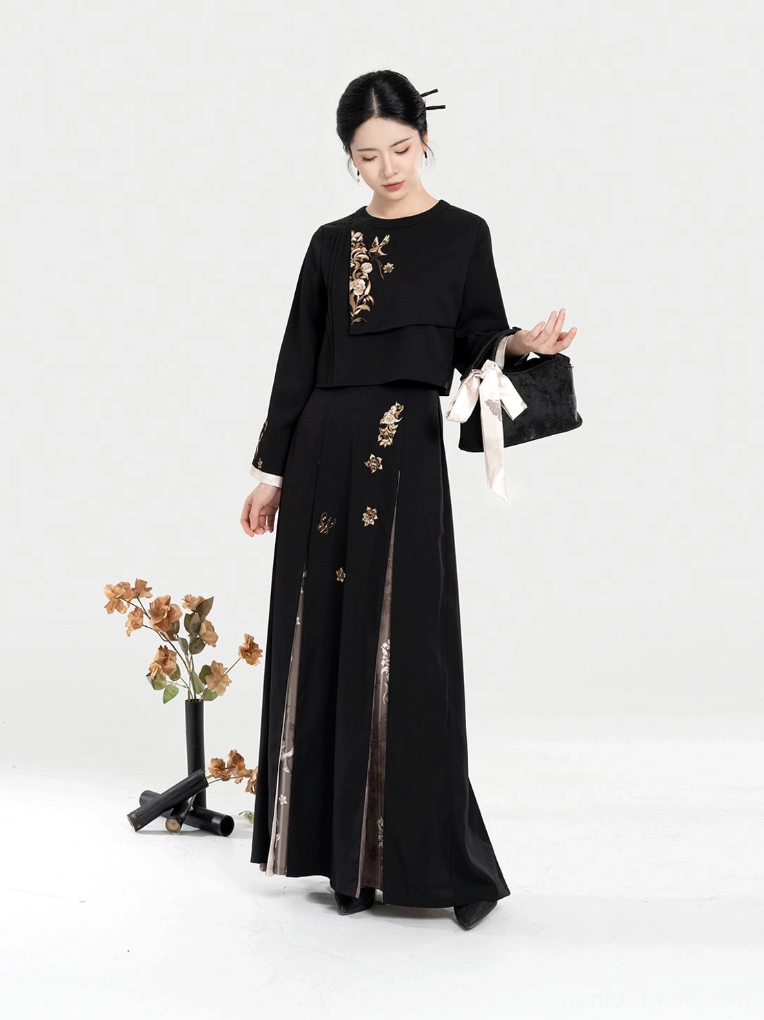 Side view of a black and gold embroidered modern Hanfu dress set showing the layered pleated skirt, side slit, floral panels, and traditional-inspired silhouette