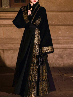 Front partial view of black and gold modern Hanfu clothing showing the embroidered cropped cross-collar jacket, wide sleeves, and vertical gold floral Mamian skirt panels