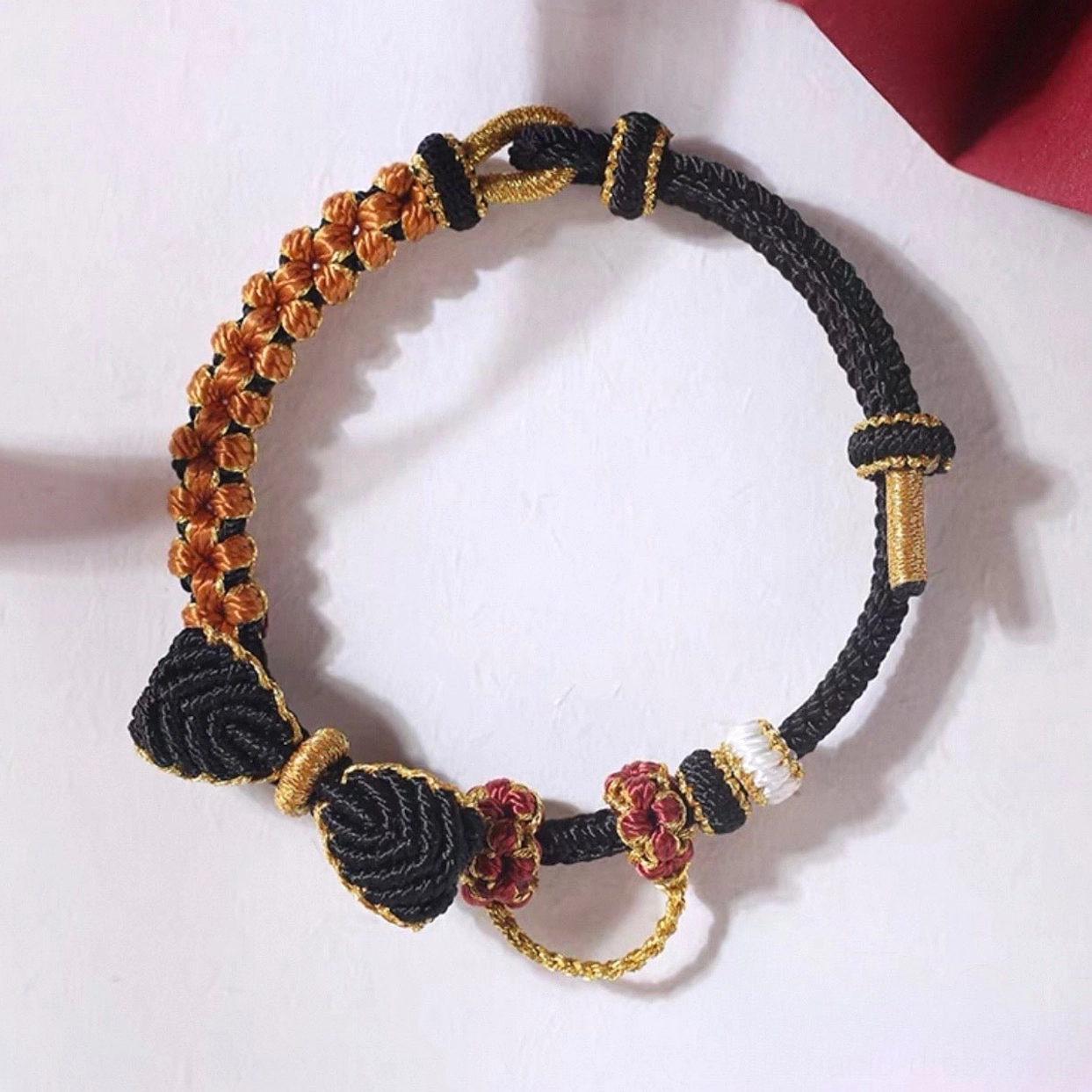 Black handwoven Chinese knot bow bracelet with bronze-gold floral knot charms and contrast braided cord