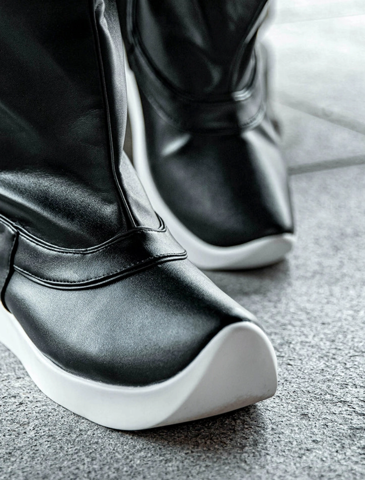Close front view of black Hanfu boots worn outdoors, showing glossy microfiber leather upper, raised toe and thick white platform sole
