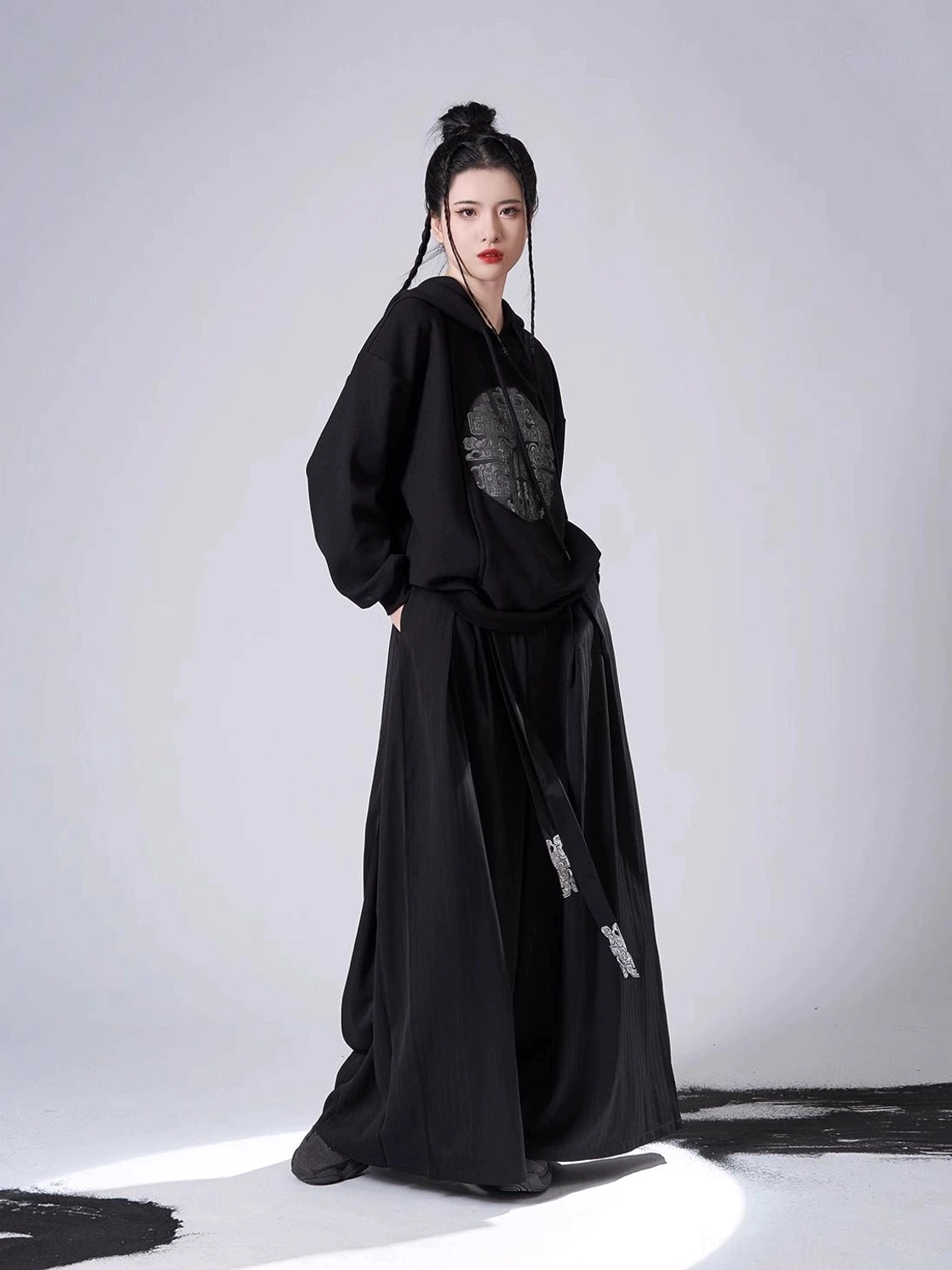 Side view of a relaxed black Hanfu hooded sweater paired with flowing wide-leg pants and embroidered tassel trim