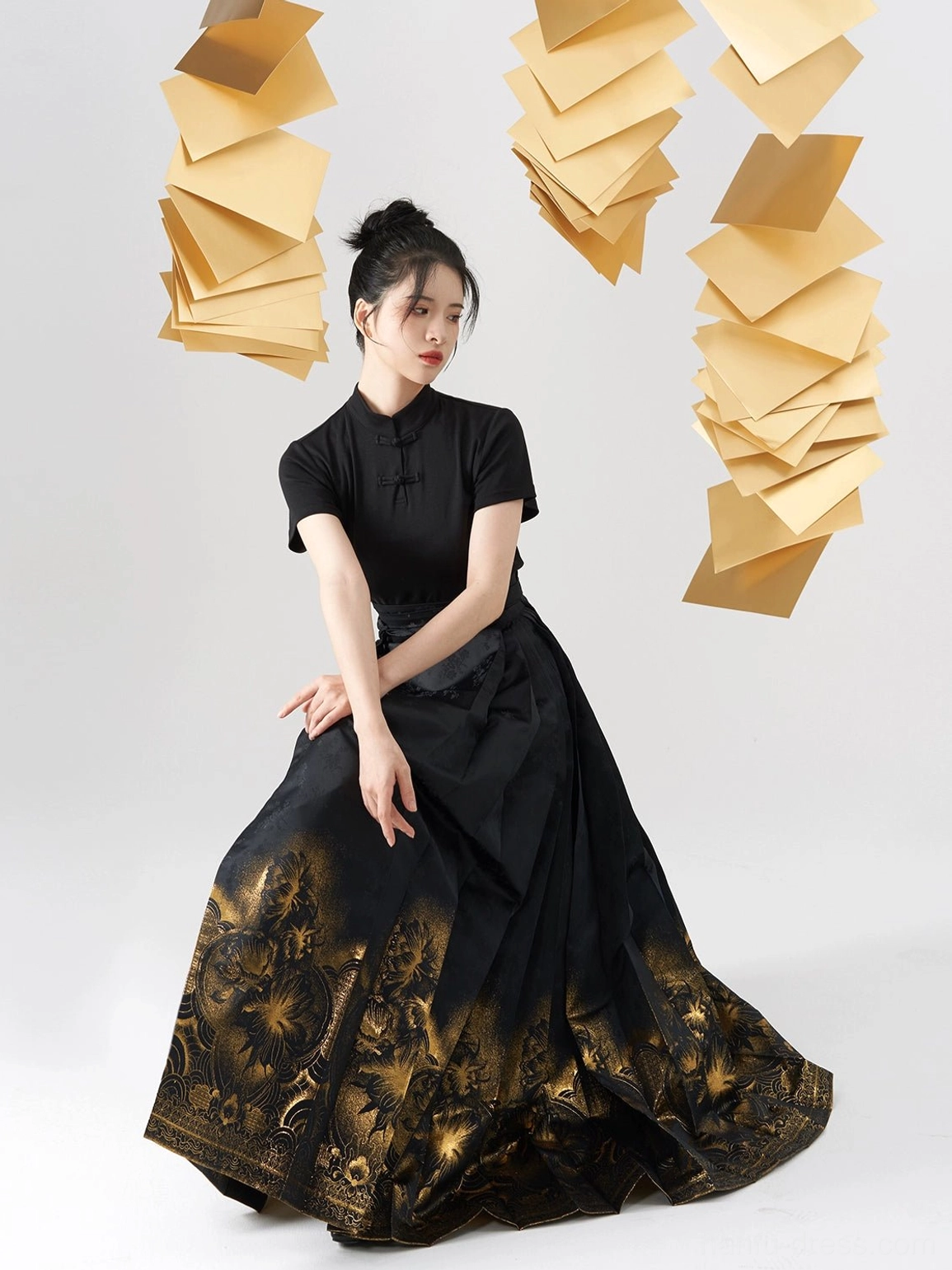Side seated view of a black Hanfu-inspired blouse with flowing pleated mamian skirt and golden epiphyllum print