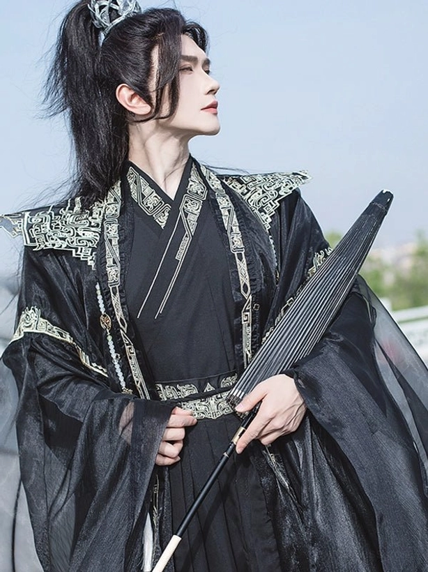 Side profile of black men's hanfu costume with gold decorative trim, flowing sleeves, silver hair crown, and black folding fan