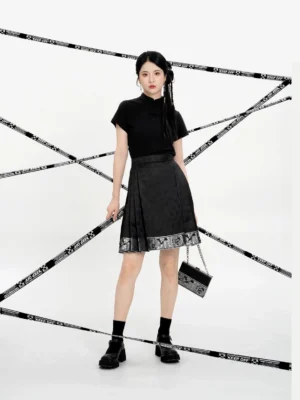 Front view of a model wearing a black Ming-inspired mini mamian skirt with a Chinese-style blouse, woven geometric texture, and decorative silver-patterned hem