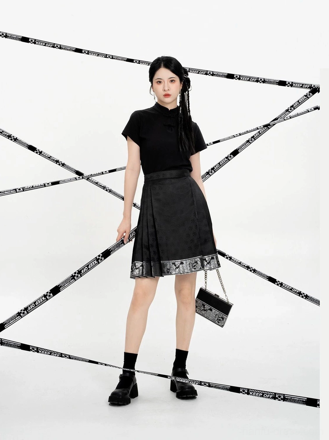 Front view of a model wearing a black Ming-inspired mini mamian skirt with a Chinese-style blouse, woven geometric texture, and decorative silver-patterned hem