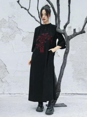 Side front view of a black modern Chinese-style embroidered dress with corduroy-textured fabric, hidden side pockets, three-quarter sleeves, and relaxed maxi-length fit