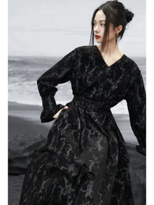 Three-quarter view of a black modern Hanfu chenille jacquard maxi dress with matching waist sash, V-neckline, long loose sleeves, and textured fabric