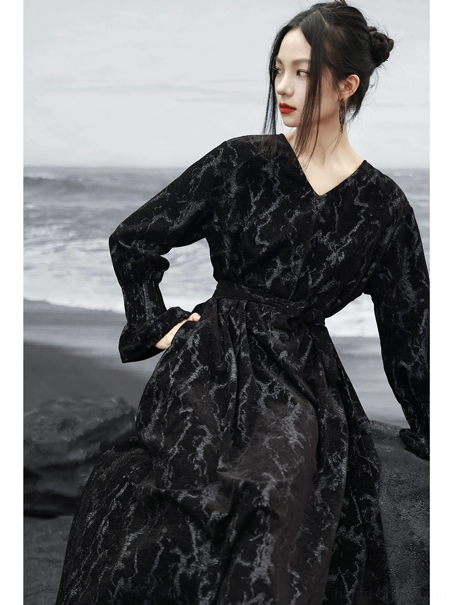 Three-quarter view of a black modern Hanfu chenille jacquard maxi dress with matching waist sash, V-neckline, long loose sleeves, and textured fabric