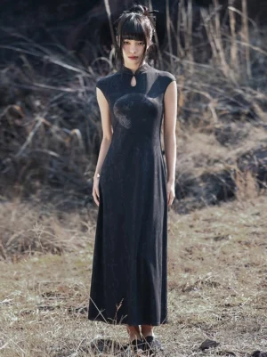 Black modern Hanfu cheongsam maxi dress shown from the front on an Asian model, featuring a Mandarin collar, fitted silhouette, subtle tonal Chinese-inspired pattern, and flowing long skirt in a natural grassland setting