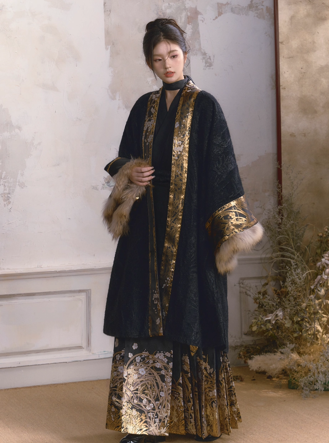 Woman wearing a black modern Hanfu coat with gold botanical trim over a high waisted embroidered mamianqun skirt in a vintage studio setting