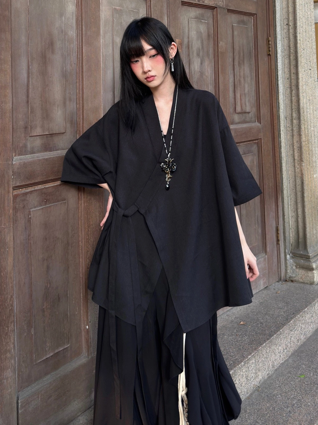 Three-quarter view of a black modern Hanfu cross-collar cardigan with loose draped silhouette and relaxed half-sleeve design