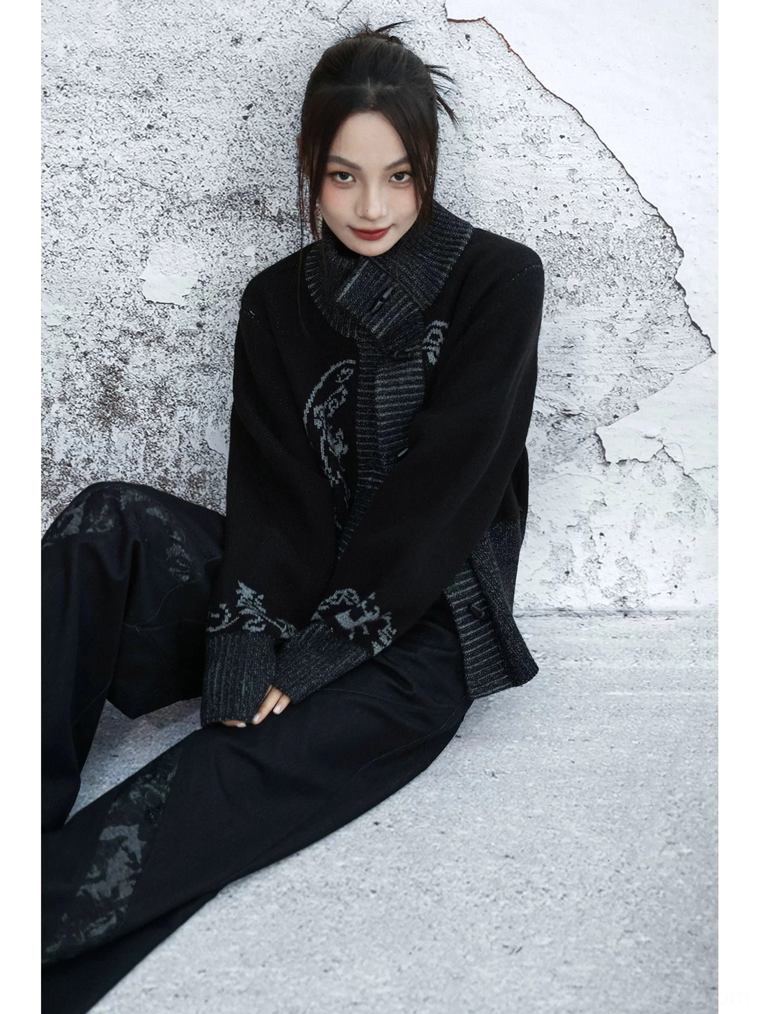 Side seated view of relaxed black Modern Hanfu cardigan showing patterned sleeve details and oversized knit silhouette