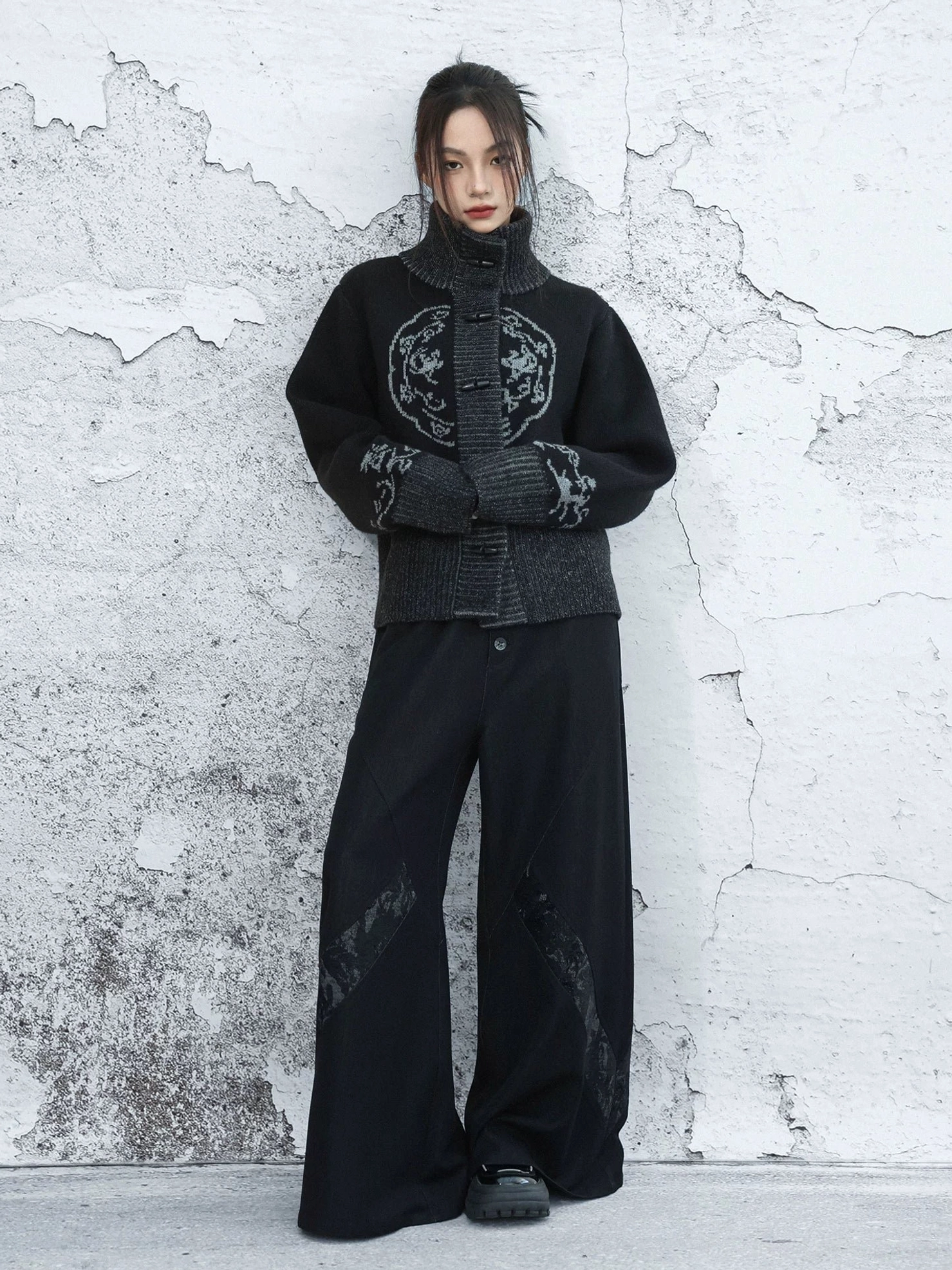 Full body front view of black New Chinese Style knit cardigan with stand collar and frog buttons paired with printed wide leg trousers