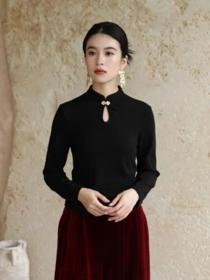 Black modern Hanfu ribbed knit top with stand collar teardrop cutout and metal frog clasp shown in a front full-body outfit view