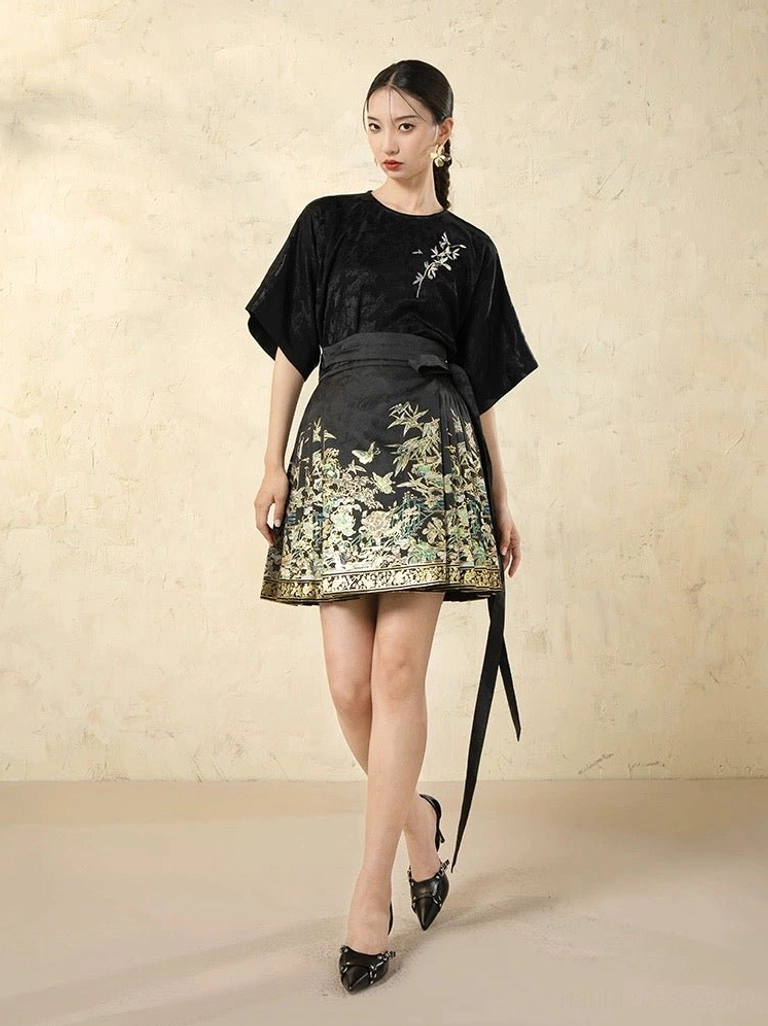Black satin modern Hanfu top with embroidered foliage motif, dolman sleeves, and short horse-face skirt with gold hem embroidery and waist sash