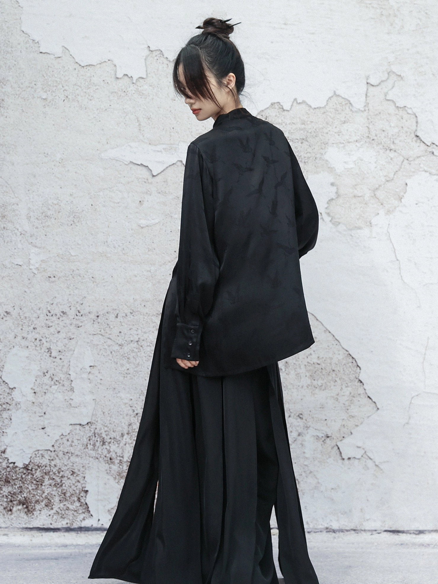 Full back view of a black modern Hanfu satin long sleeve top with clean back design, relaxed silhouette, subtle dark pattern, and buttoned sleeves