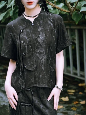 Close-up of black modern Chinese style Hanfu shirt with silver crane embroidery, stand collar, dark frog buttons, jacquard texture, and side strap detail