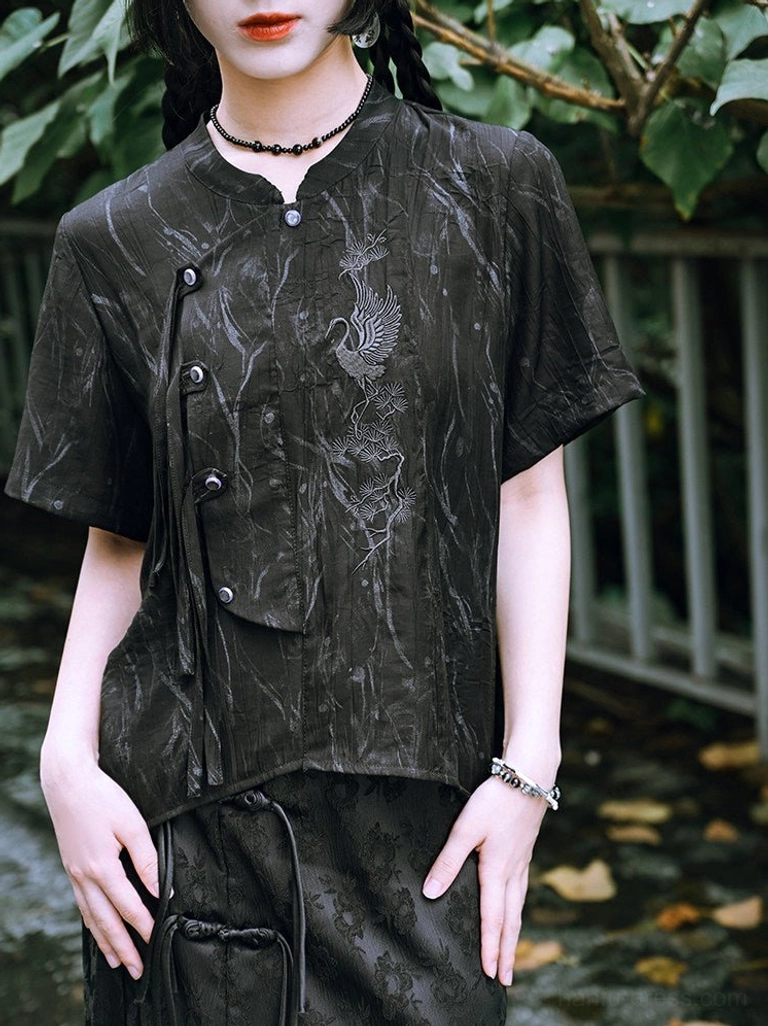 Close-up of black modern Chinese style Hanfu shirt with silver crane embroidery, stand collar, dark frog buttons, jacquard texture, and side strap detail