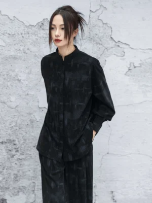 Black modern Hanfu stand collar long sleeve top shown from a left three-quarter front view with subtle dark block texture and oversized relaxed silhouette