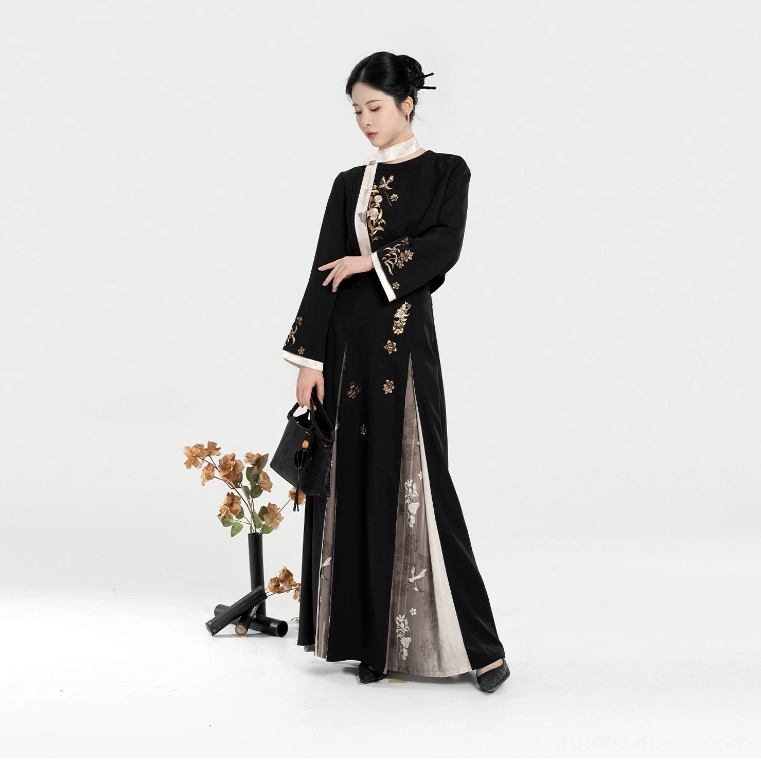 Side view of a black modern Hanfu two-piece set with golden floral embroidery, white jacket trim, embroidered skirt side panel, and flowing pleated silhouette
