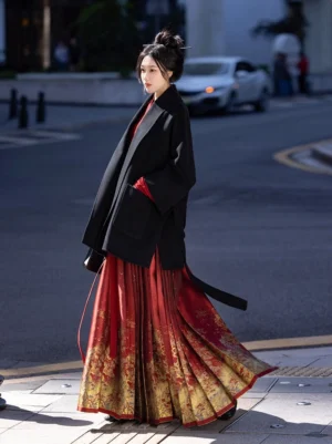 Black modern Hanfu wool coat with waist tie styled with a red top and printed horse-face skirt on a city street