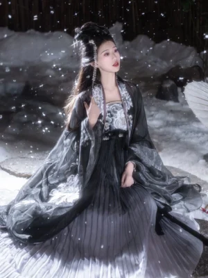 Black Peony Tang Dynasty style Heziqun Hanfu dress set shown in a three-quarter seated pose, featuring sheer black wide sleeves, embroidered peonies, and a gray gradient pleated skirt in snow
