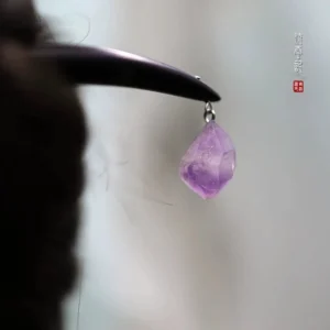 Close-up of natural purple amethyst pendant and silver-tone connecting ring on black wooden Chinese hair stick