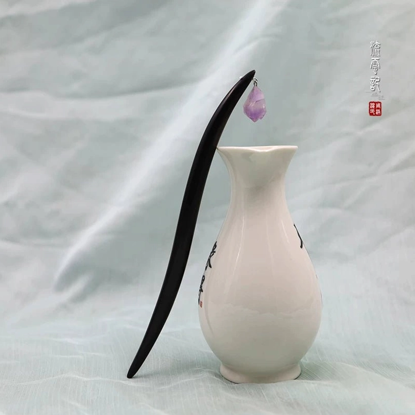 Black sandalwood amethyst Chinese hair stick displayed beside a white porcelain vase on a soft light fabric background