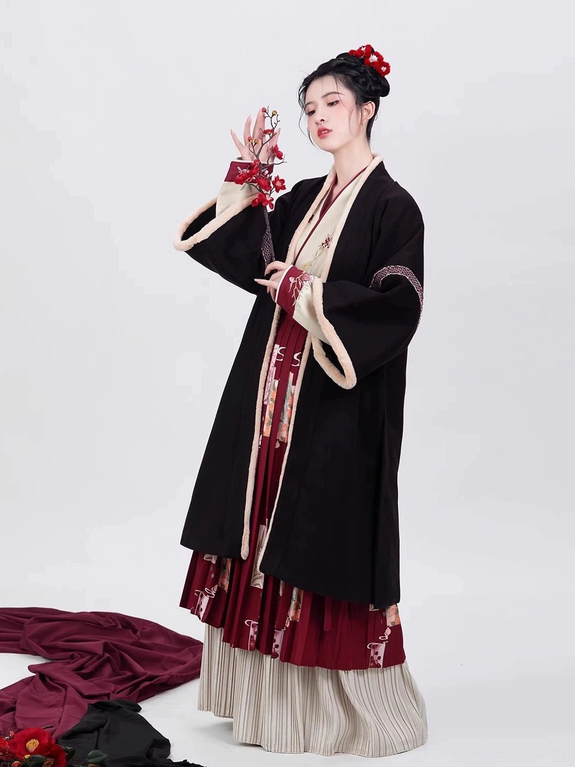 Black Song Dynasty modern Chinese New Year hanfu robe styled with an embroidered inner top, red floral pleated skirt, beige fuzzy trim, and wide sleeves