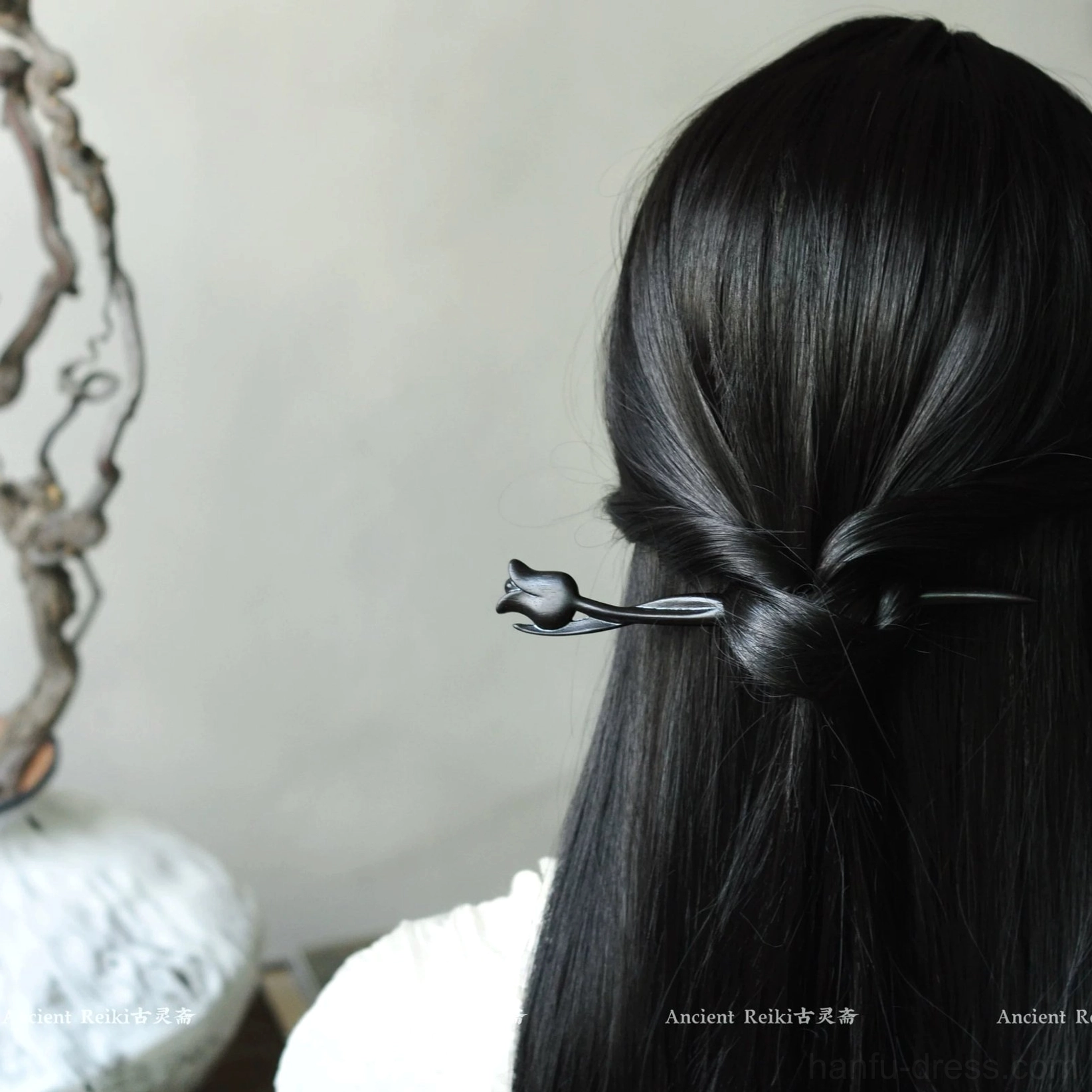 Black tulip traditional Chinese hair accessory styled with a low half-up hairstyle against a natural decorative background