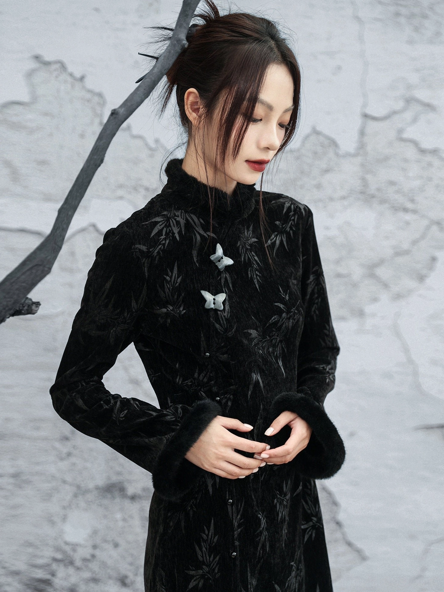 Close-up view of black velvet modern Hanfu cheongsam dress with embossed bamboo leaf pattern, fluffy cuffs, stand collar, and ceramic-style frog fasteners