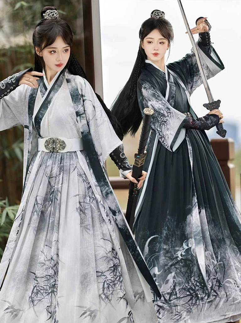Two female models wearing black and white ink-wash Wei Jin Dynasty Qiyao Ruqun Hanfu sets with traditional Chinese painting patterns and ornate metal waist belts in an outdoor garden