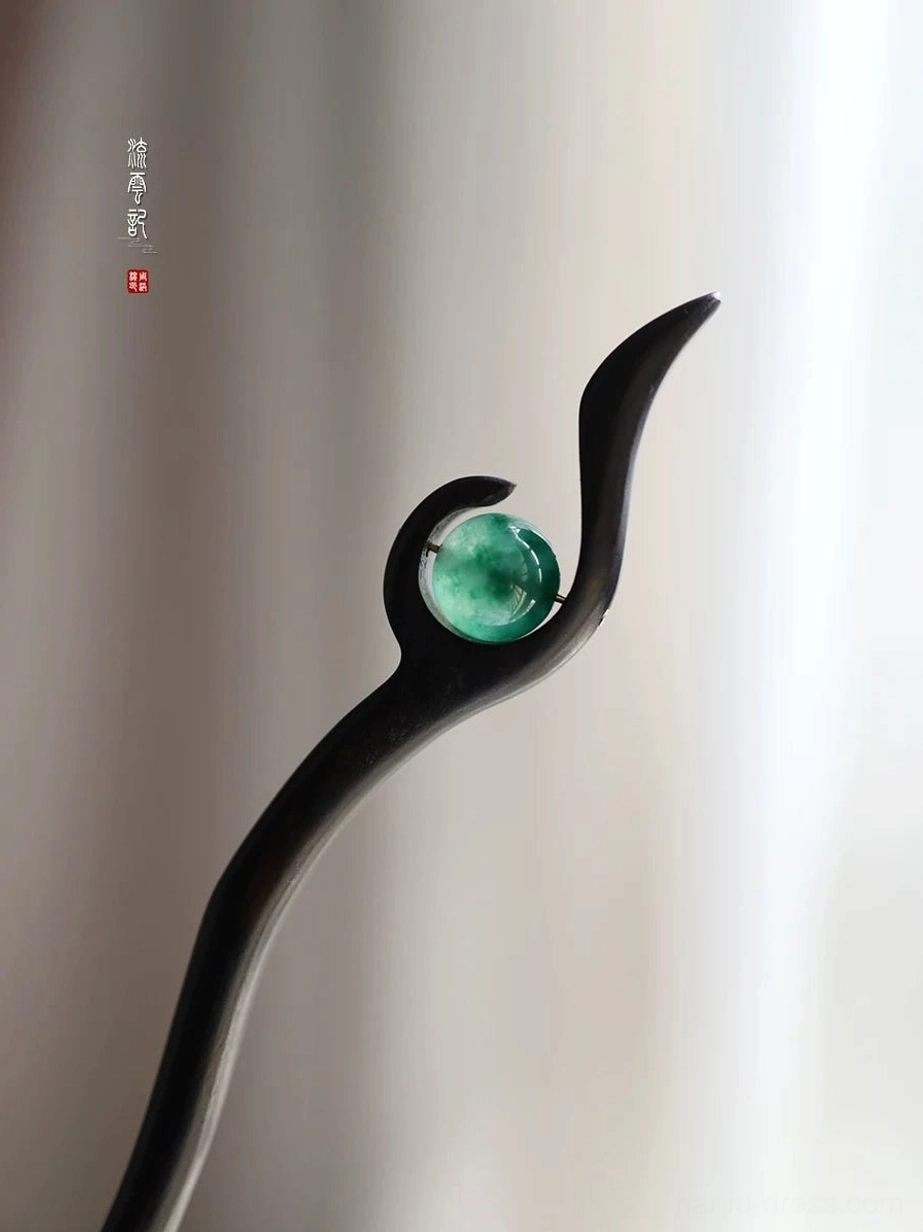 Black polished wood Chinese hair stick with round green jade ornament and graceful swirl-inspired curved top on a soft curtain background