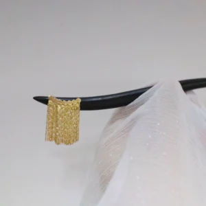 Black wooden Chinese hair stick with a flowing gold tassel held against shimmering white Hanfu clothing