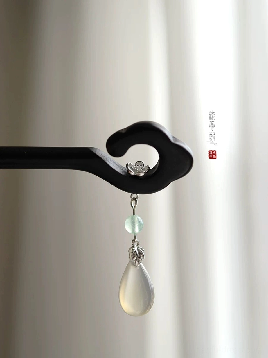 Side close-up of black wooden cloud Chinese hair stick with silver-tone flower ornament, green bead, and milky teardrop pendant