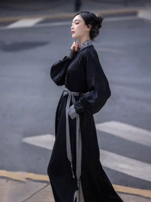Black Wuxia-inspired Chinese style long dress with relaxed wide sleeves contrast embroidered collar grey tassel waist sash and flowing maxi silhouette side view