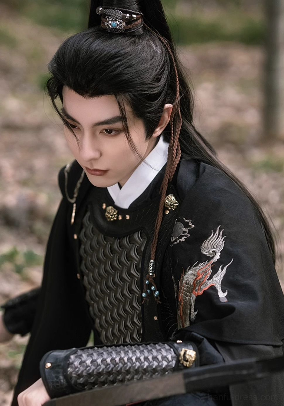 Overhead close-up of black xianxia warrior hanfu for men showing white inner collar, embroidered shoulder pattern, gold arm armor, and hair crown