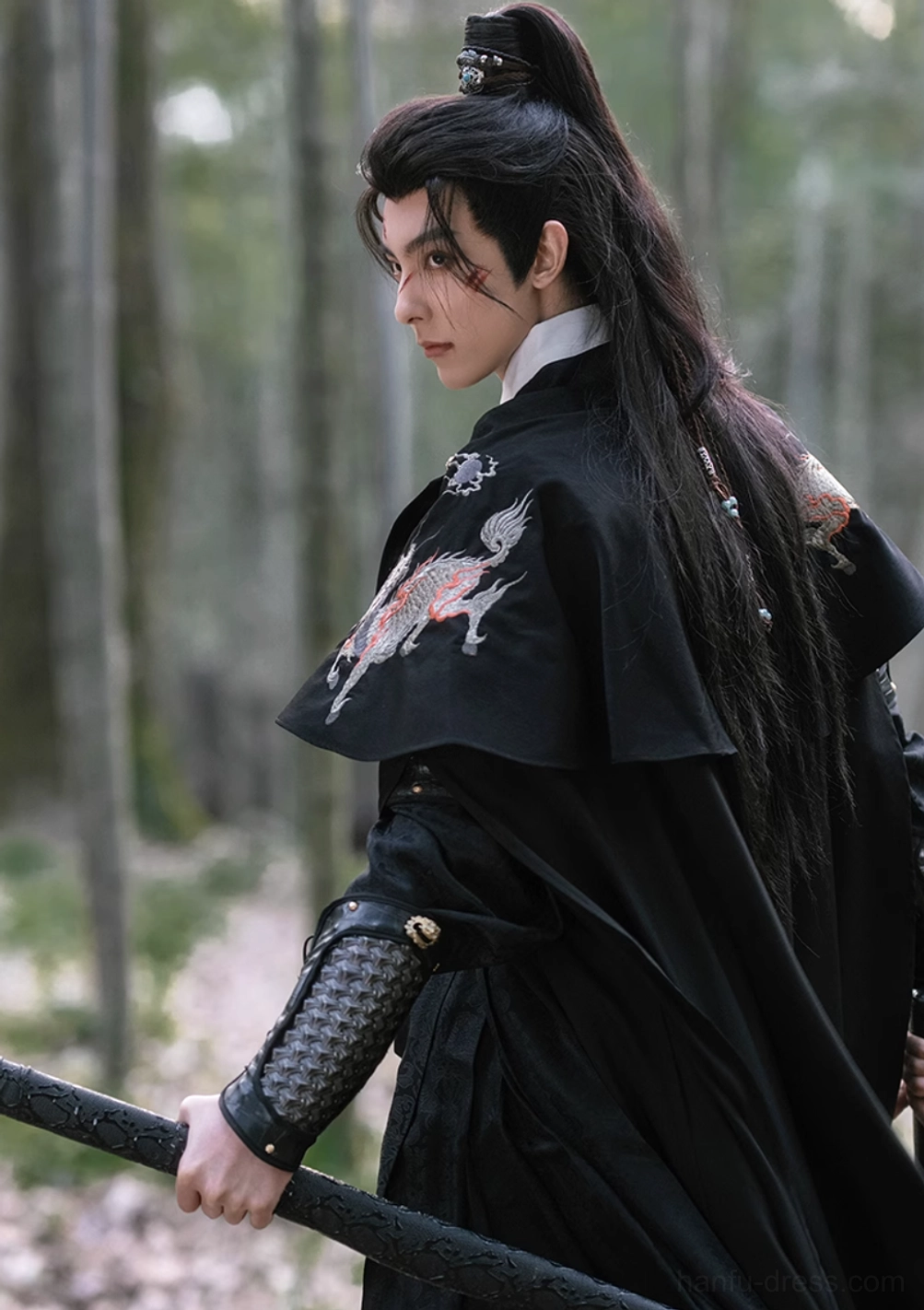 Rear side view of black xianxia warrior hanfu costume with flowing cloak, qilin embroidered shoulder detail, and high ponytail in bamboo forest
