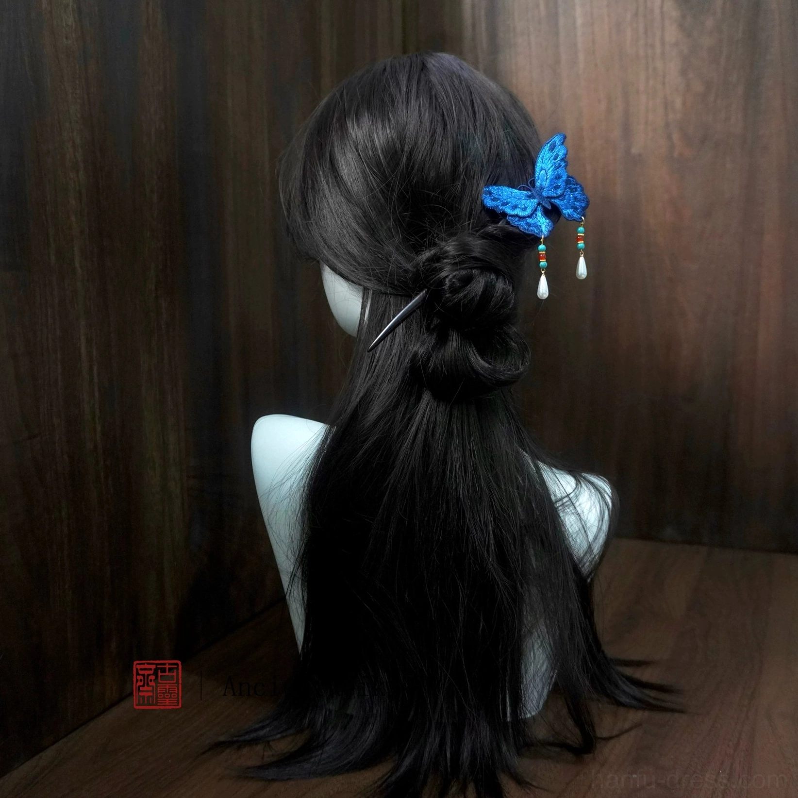 Back view of blue butterfly Chinese hair stick worn in a coiled bun hairstyle with cascading beaded tassels