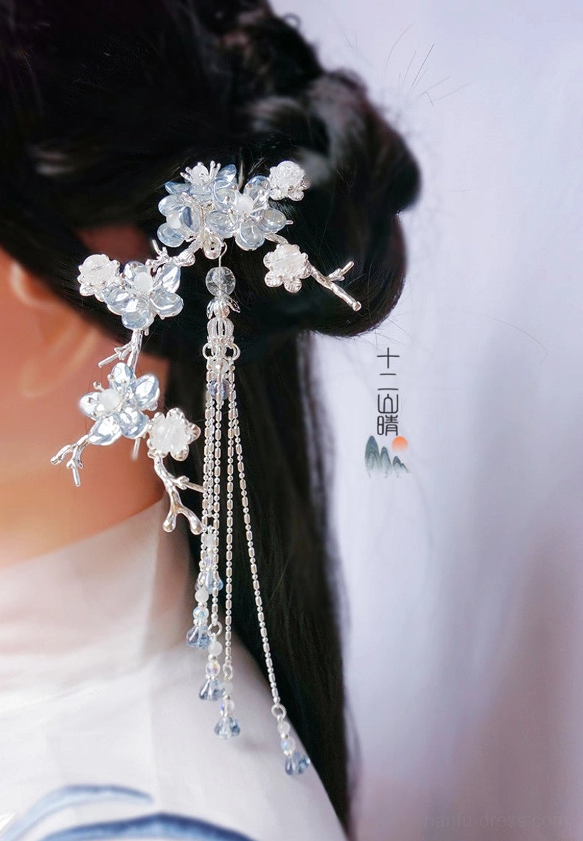Side view of a blue and clear crystal plum blossom hairpin with hanging silver chain tassel in a traditional hanfu hairstyle