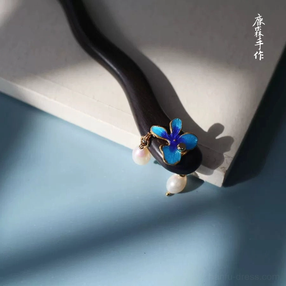 Close-up of blue cloisonne flower and pearl drop details on a traditional sandalwood Hanfu hair stick