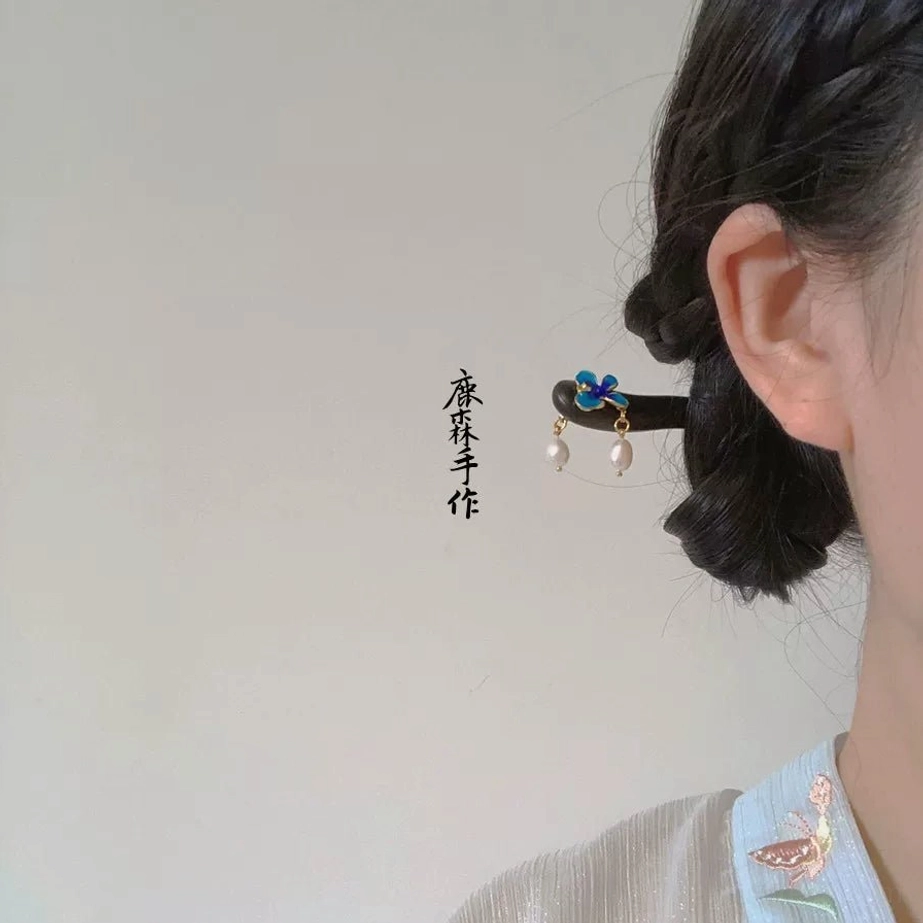 Blue cloisonne flower sandalwood Chinese hair stick worn in a coiled bun with pearl drop accents and Hanfu-inspired styling