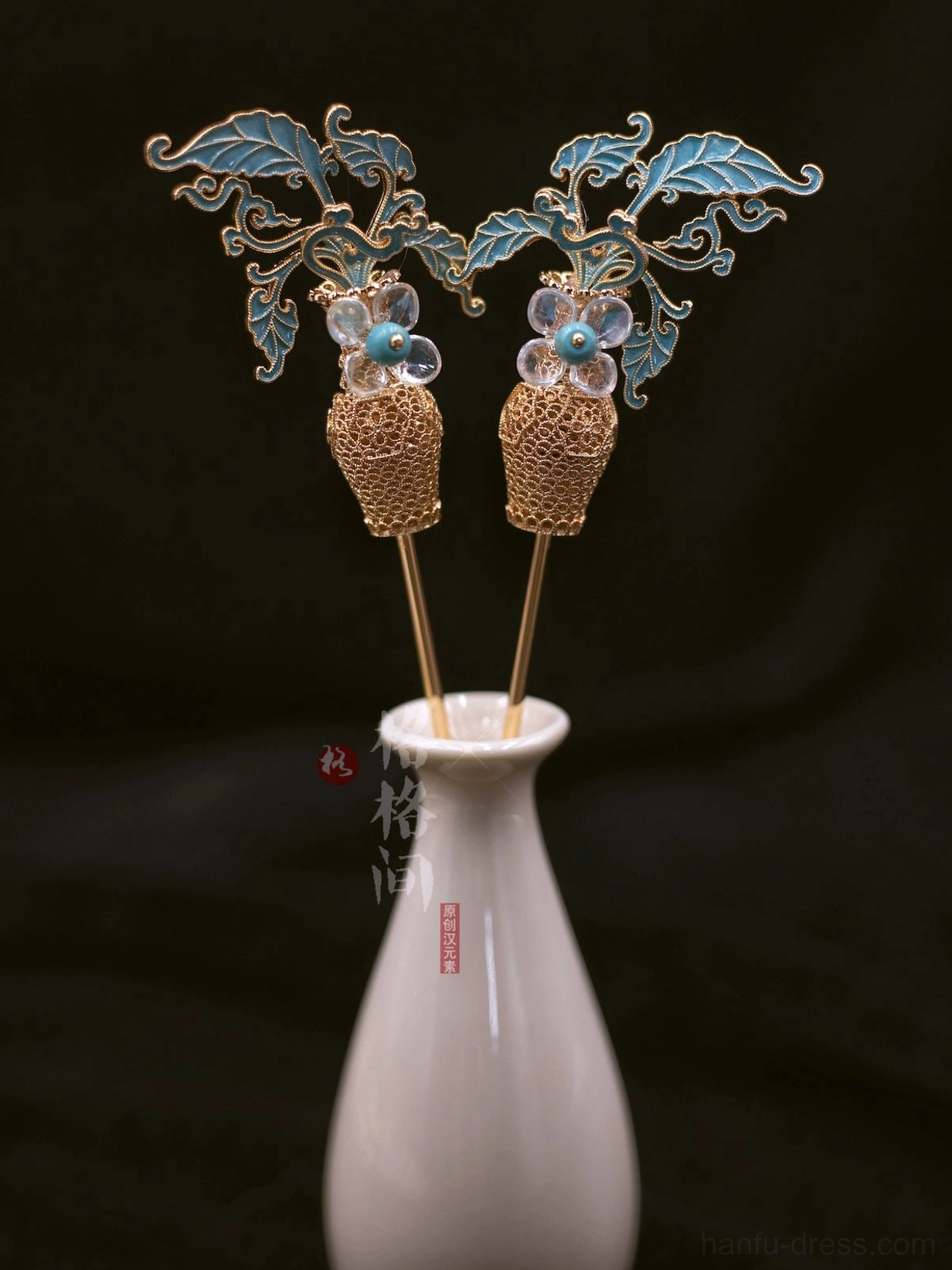 Blue cloisonne leaf and pearl tassel Hanfu hair pin pair displayed on a white ceramic vase